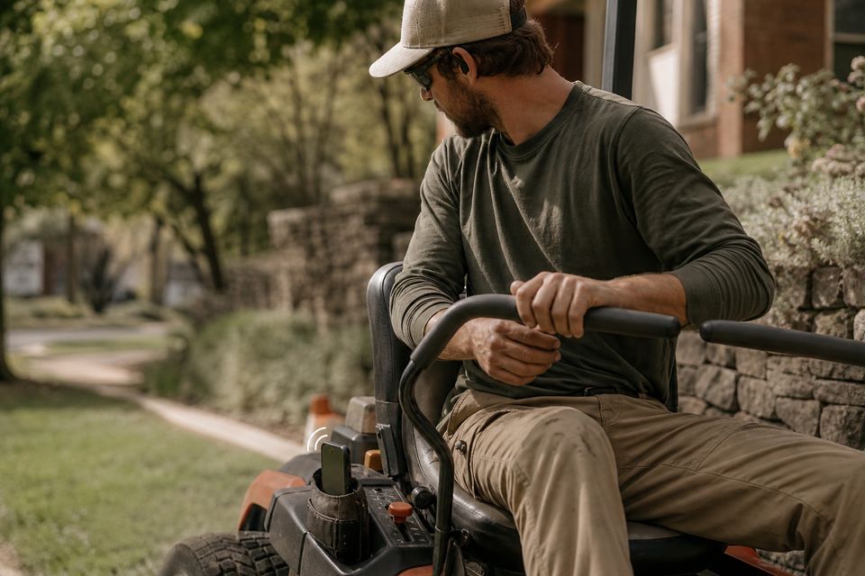 Landscaper on a mower with a phone vibrating in a tool belt