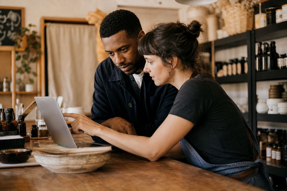 Two people at a shop counter reviewing a laptop together