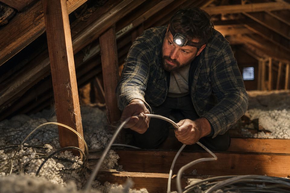Electrician pulling cable through attic joists