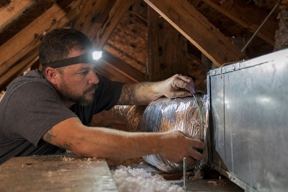 HVAC technician securing ductwork in an attic